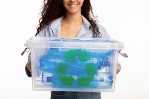 Plastic Recycling. Unrecognizable Lady Holding Container With Recycle Symbol Full Of Litter Rubbish Standing On White Studio Background. Waste Sorting And Junk Disposal. Cropped photo