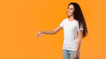 Hello. Side View Of Cheerful Woman Offering Hand For Handshake Greeting Aside Standing Posing Over Yellow Studio Background. Nice To Meet You. Lady Doing Shaking Hands Gesture. Panorama, Free Space photo