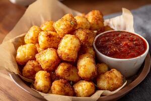 Tasty crispy cheese curds with flavorful marinara sauce ready to eat on white background photo