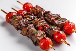 Juicy beef kababs with charred cherry tomatoes on white plate photo