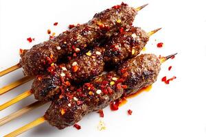 Close up of grilled kofta beef skewers topped with flavorful chili oil and seasoning photo