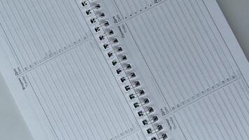 Minimalist close-up of an open spiral-bound weekly planner featuring days of the week in both Russian and English. Perfect for illustrating organization, productivity, and time management in international or bilingual settings. Ideal for business, educati photo