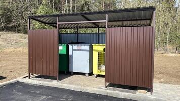 Three garbage bins for separate waste disposal are located in a closed area. photo