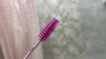 A pink brush with a pink handle is held up photo