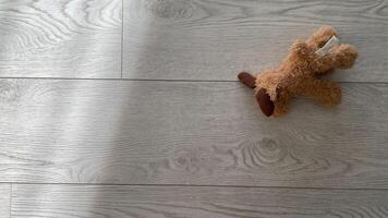 brown furry texture toy lies on gray wooden floor in apartment photo