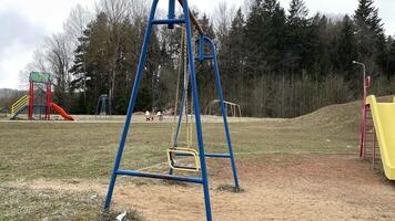 Blue swings on the playground. Depressive autumn landscape in rainy weather. photo