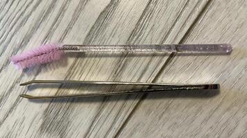 A pair of tweezers and a pink brush photo