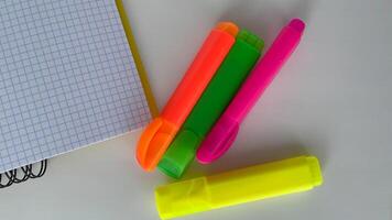 Brighten up your workspace with this colorful set of neon highlighters and a squared graph notebook, perfect for students, teachers, and office professionals. This eye-catching image is ideal for educational, organizational, or productivity-themed project photo