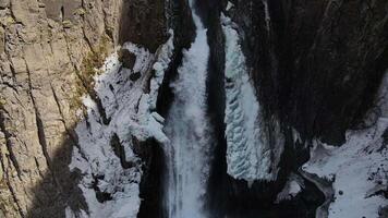 Winter drone view of Karakaya-Su waterfall. A powerful stream bursts out of the rocks. Icicles around the waterfall video
