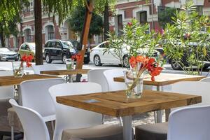 Beautiful Old Street in Kyiv With Deciduous Trees and Cafe Tables, Ukraine. Cute Design, Flowers on the Table, Flower Pots Along the Road photo