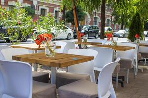 Beautiful Old Street in Kyiv With Deciduous Trees and Cafe Tables, Ukraine. Cute Design, Flowers on the Table, Flower Pots Along the Road photo