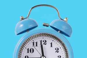Retro Alarm Clock. Close up One Classic Alarm Clock on a Blue Background photo
