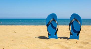 Blue flip-flops resting on the sand at the beach photo
