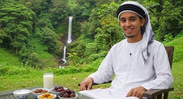 Portrait of a young Arab man with sweets at a table photo