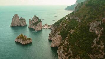 Serene cove nestled between dramatic rock formations and a lush hillside. The secluded bay is dotted with leisure boats, hidden beaches below. video