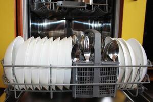 Dishwasher with plates. Close up of open dishwasher with clean dishes. photo