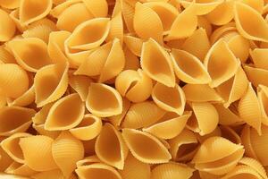 Figured paste in the form of a cochlea. Italian pasta conchiglie abstract backdrop. Texture. photo