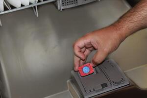 A man puts a pill in a container in a dishwasher. photo