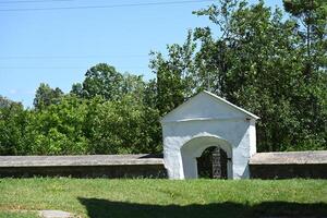 a white building with a gate in the middle of a field photo