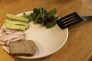 preparing breakfast on a plate meat, greens, cucumbers photo