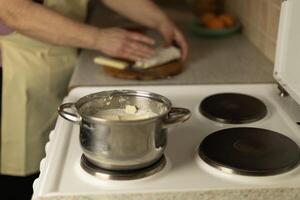 semi-melted butter in a saucepan on the stove, in the background the hands of a senior woman photo