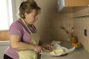 Senior woman in an apron preparing sweet butter for heating for preparing ghee butter photo