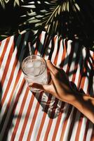 Refreshing Drink Held on Striped Fabric With Tropical Influences in Bright Sunlight photo