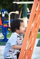 A 2-year-old Asian boy is having fun climbing. Little child having fun on toy Climbing Wall at the playground outdoor on a sunny day. photo