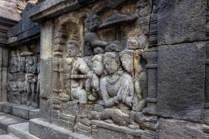 Ancient stone carvings showing detailed human and symbolic figures on a temple wall. photo