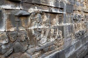 Stone reliefs depict ancient figures in intricate detail on a historic temple wall. photo