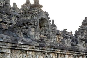 A headless Buddha statue sits in a stone niche on Borobudur temples ancient upper terrace. photo