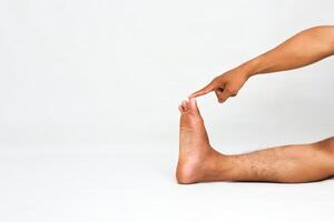 Close-up of a Man Pointing at his Toe Against a White Background in a Studio photo
