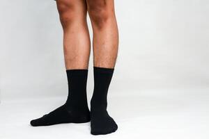 Studio shot showcasing a man's lower legs and feet adorned with sleek black socks against a pristine white backdrop photo