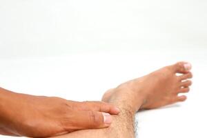 Close-up of a Man's Hand Massaging or Checking His Ankle for Pain or Injury Isolated on White photo