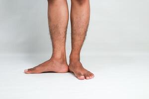 Close-up shot of a person's lower legs and feet against a plain, clean backdrop, showcasing healthy skin photo