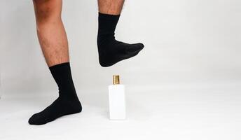 Quirky studio shot of a man's legs and a perfume bottle in a playful, humorous concept photo