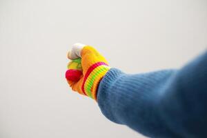 Close-up of a hand wearing a colorful glove against a plain background focusing on the fist photo