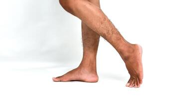 Studio shot of dark-skinned legs in motion, showcasing a step forward against a clean white backdrop photo