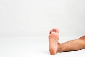 Close-up of a bare male foot on a white background, showcasing foot care and anatomy in a simple, isolated setting photo