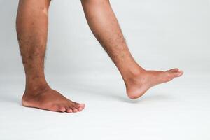 Close-up view of a person's legs and feet demonstrating a walking motion on a white backdrop photo