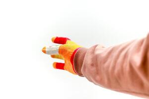 A gloved hand reaches out, with a bandaged finger, against a stark white background, offering assistance photo