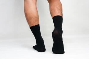 A man wearing black socks on a white background in a studio setting for advertising photo