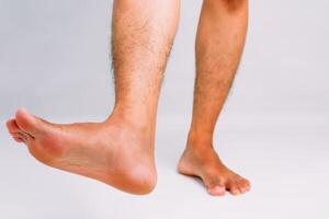 Close-up of a man's legs and feet against a plain background, showcasing foot flexibility photo