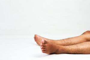 Man lying on his back with legs and feet in the air against a white background showing relaxation photo