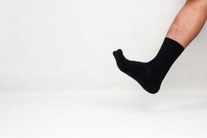 Man's leg wearing a black sock against a plain white background, creating a minimalist and modern visual concept photo