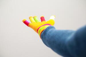 Brightly colored glove hand extended against a plain white backdrop conveys a sense of reaching photo