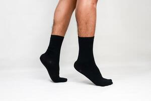 A close-up studio shot showcasing a man's legs and feet wearing black socks on white background photo