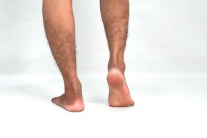 Close-up of a man's hairy legs and feet from the rear isolated against a white background emphasizing the lower extremities photo