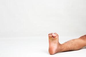 Close-up shot of a man's bare foot showing toes and skin texture in a clean studio setting on white backdrop with lots of negative space photo