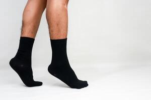 Close up of a man's legs in black socks walking on a white studio backdrop showing the detail and texture of the material photo